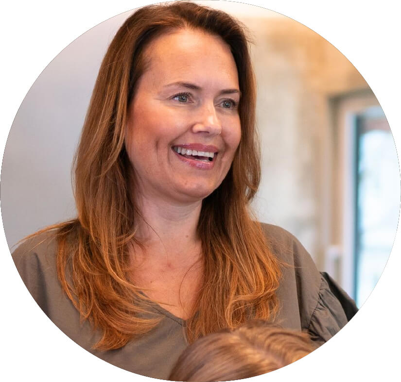 Friseurin im Salon lächelt und spricht mit Kundin – steht für ihre Empfehlung von Hair Luxious als effektive Lösung gegen Haarausfall und für gesünderes Haar.